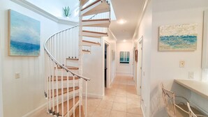 A spacious interior with a spiral staircase, a dining area, and artwork on the walls. - L'escapade, Old Seagrove, Near Seaside, Private Heated Pool, Close to Beach (Seagrove Beach)