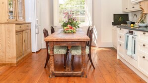 Une cuisine avec une table en bois, des placards blancs et une fenêtre donnant sur un paysage verdoyant.