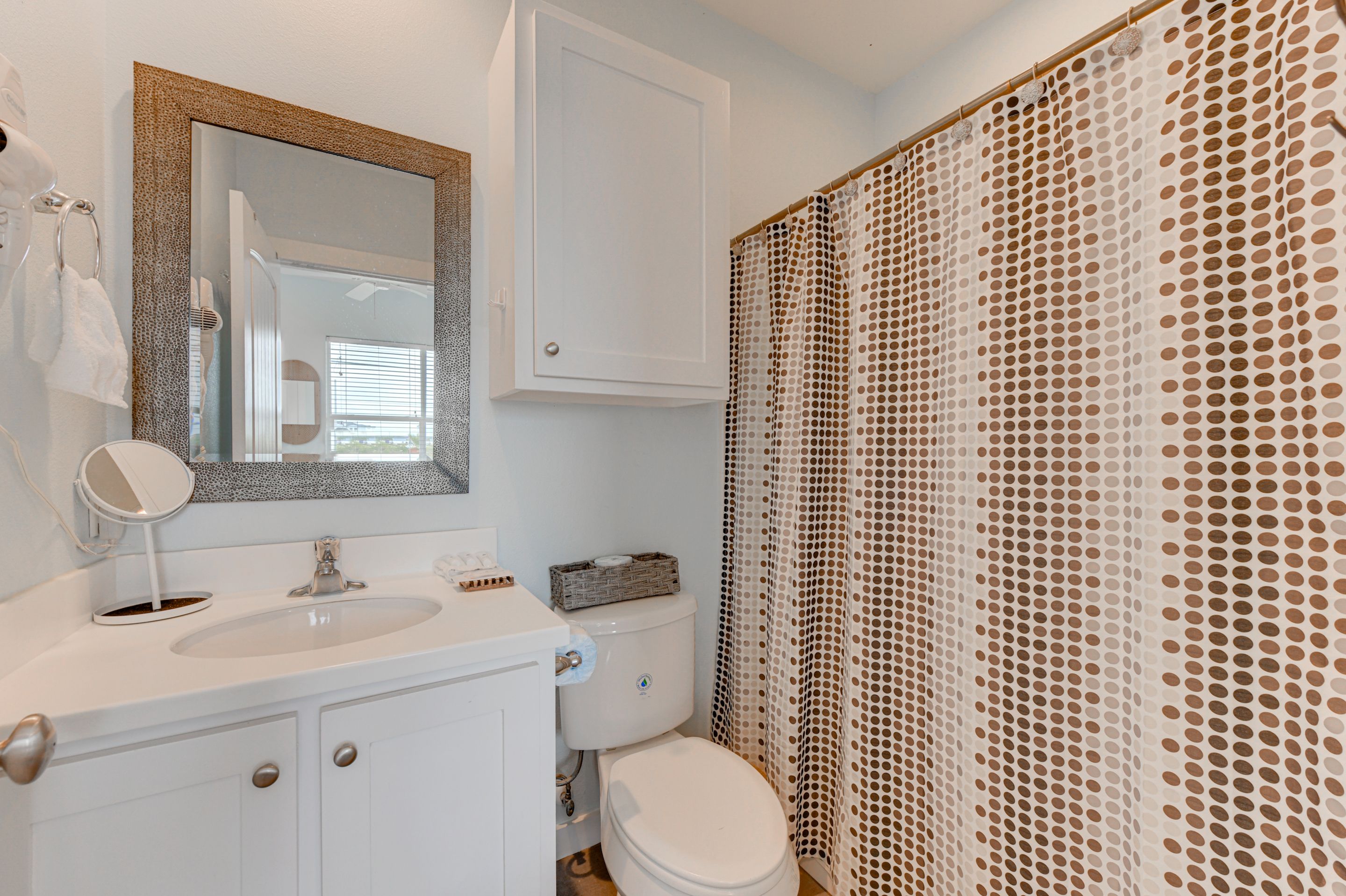 A bathroom with a white sink, mirror, and toilet.