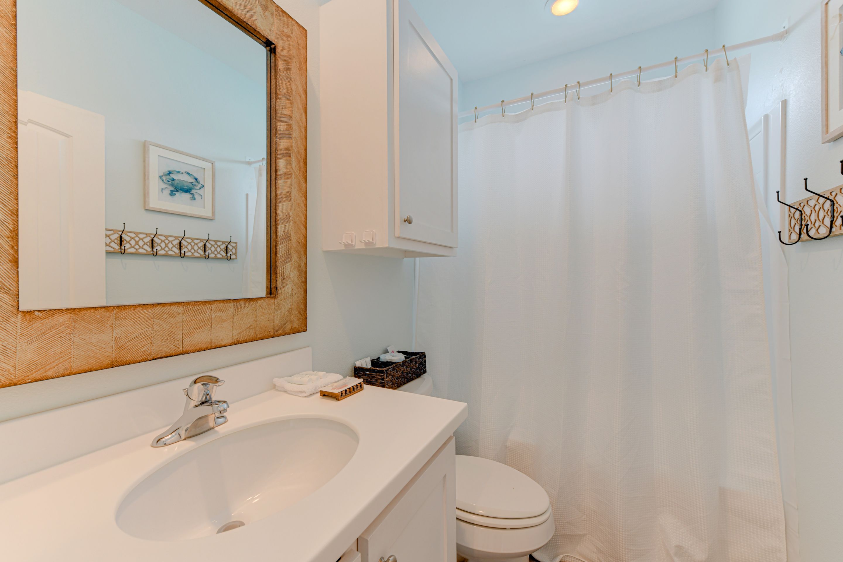 Une salle de bain avec un lavabo blanc, un miroir, des toilettes et un rideau de douche.