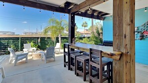 Une terrasse extérieure avec une table et des chaises en bois, un foyer et une vue sur les environs.