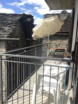 Ein Balkon mit Steinmauer, Metallgeländer und einem Tisch mit Stühlen.