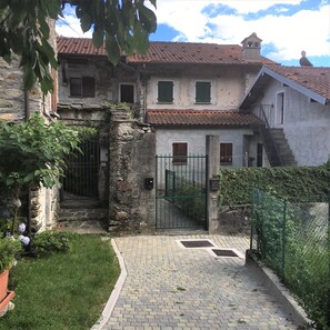 Ein rustikales Steinhaus mit Ziegeldach, einem verschlossenen Eingang und einer kleinen Treppe, die zum oberen Stockwerk führt.