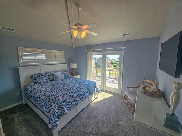 A bedroom with a bed, a ceiling fan, a window, and a view of the outdoors.