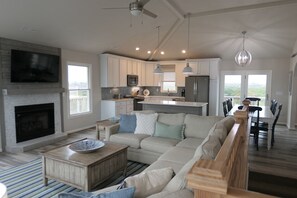 A modern living room with a fireplace, a sectional sofa, and a dining area with a view.