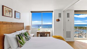 Ein Hotelzimmer mit Bett, Schreibtisch, Meerblick und Balkon.