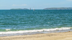 A beach with calm waters and two sailboats in the distance. - Hen Felin (Pwllheli)