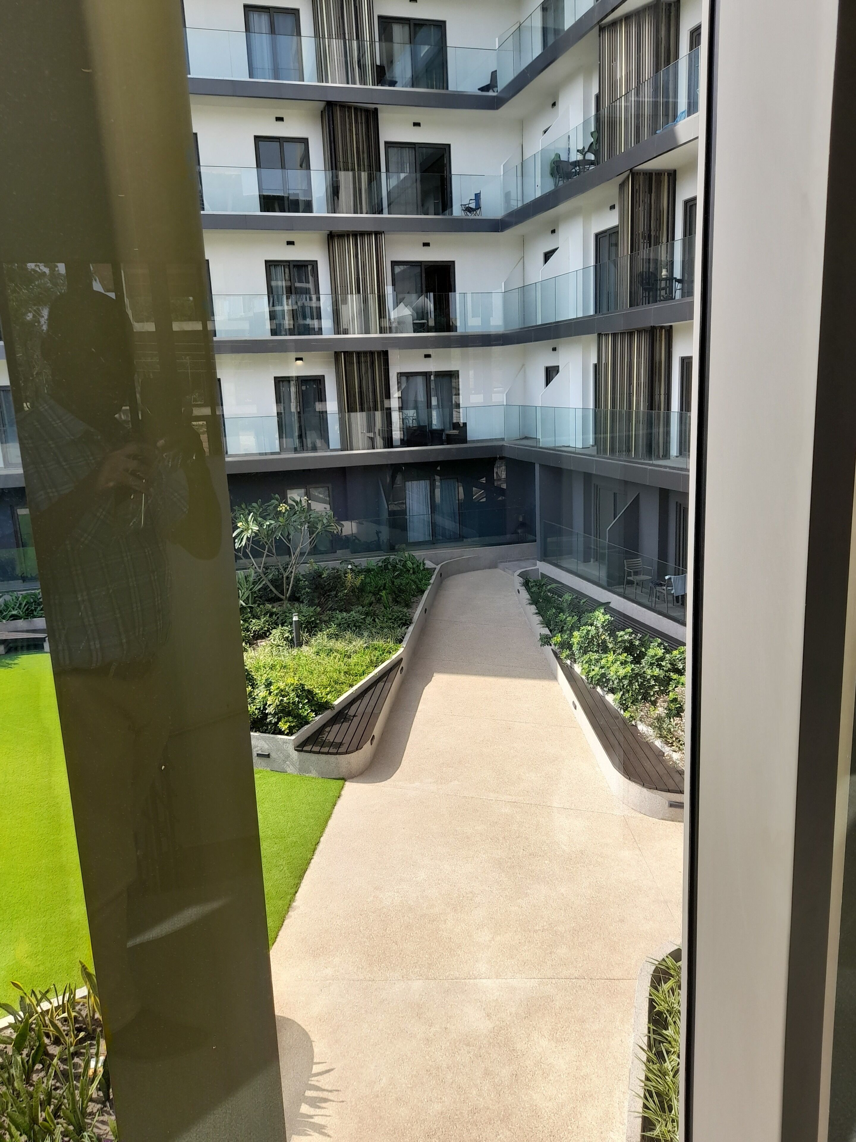 Um edifício residencial com várias andares, varandas, um pátio central e um caminho.