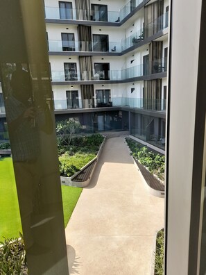 Un immeuble résidentiel à plusieurs étages, doté de balcons, d’une cour intérieure et d’un chemin.