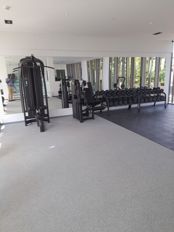 Une salle de sport équipée de matériel d’exercice, d’un miroir et d’un porte-haltères.