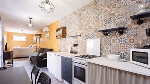 A compact kitchen with a stove, microwave, and a dining area with chairs. - Las Latas del Almendro 1 (Santiago del Teide)