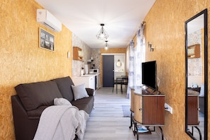 A compact living space with a sofa, a TV, and a small kitchenette.
