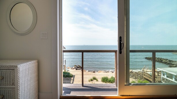 Ein Zimmer mit einer großen Schiebeglastür und Blick auf den Strand.