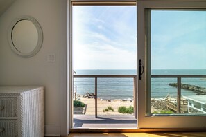 Een kamer met een grote schuifglazen deur die uitkomt op uitzicht op een strand.