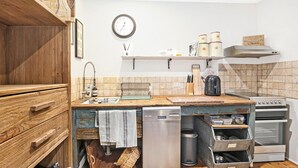 Una cocina con armarios de madera, un lavamanos, una estufa y un reloj en la pared.