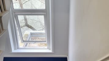 A staircase with a carpeted landing and a view of trees outside through a window.