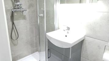 A modern bathroom with a glass-enclosed shower, a white sink, and a toilet.