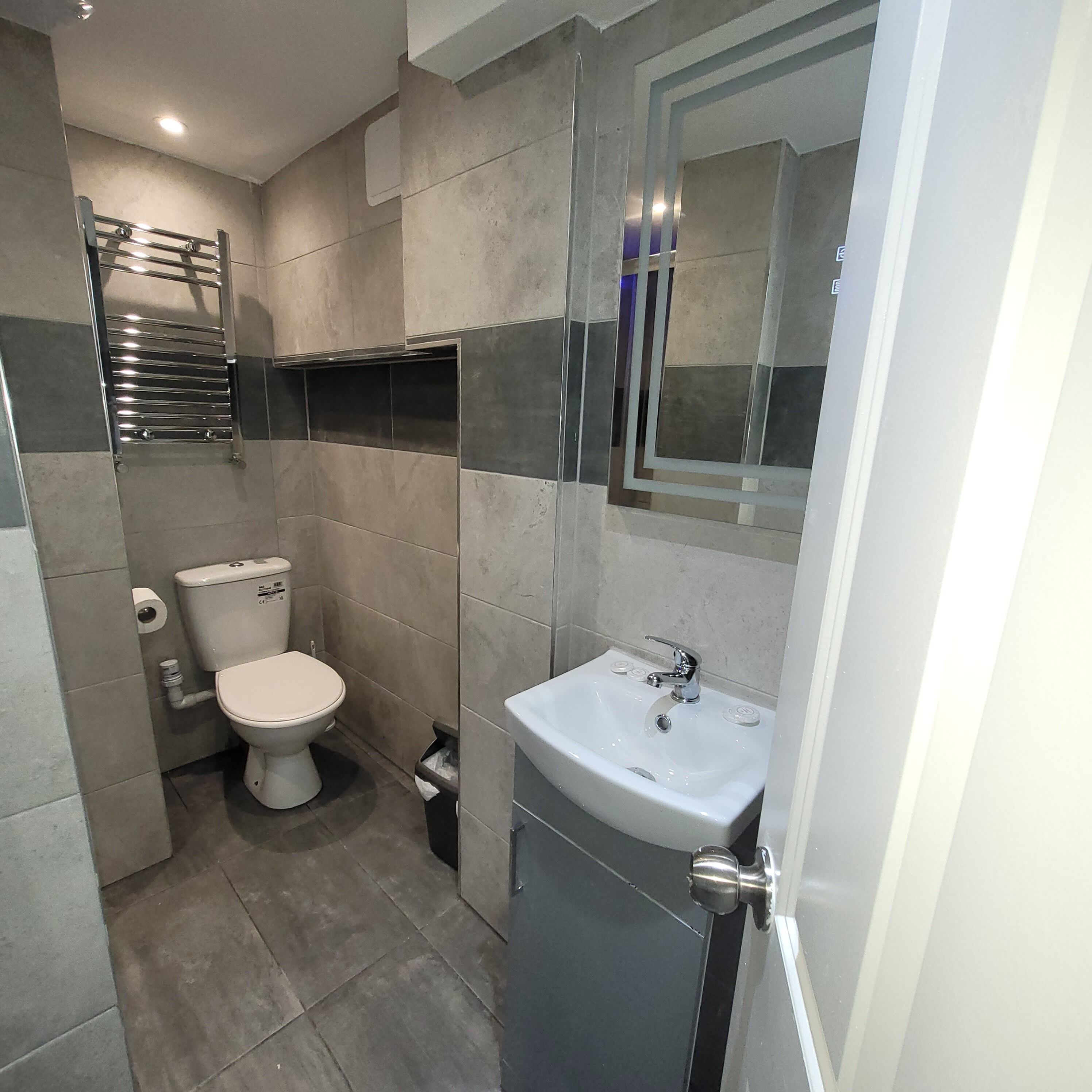 A modern bathroom with a toilet, sink, and mirror.