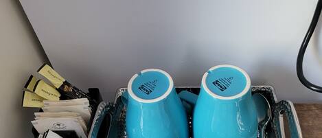 A tray with two blue mugs and several containers of semi-skimmed milk.