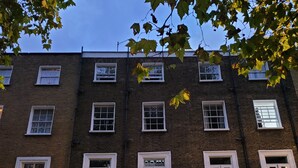 Un edificio de varios pisos de ladrillo con ventanas y balcones con marco blanco.