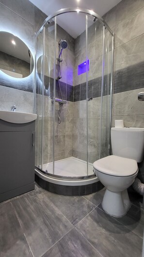 A modern bathroom with a glass-enclosed shower, a toilet, and a sink. - Argyle Square Hotel (London)