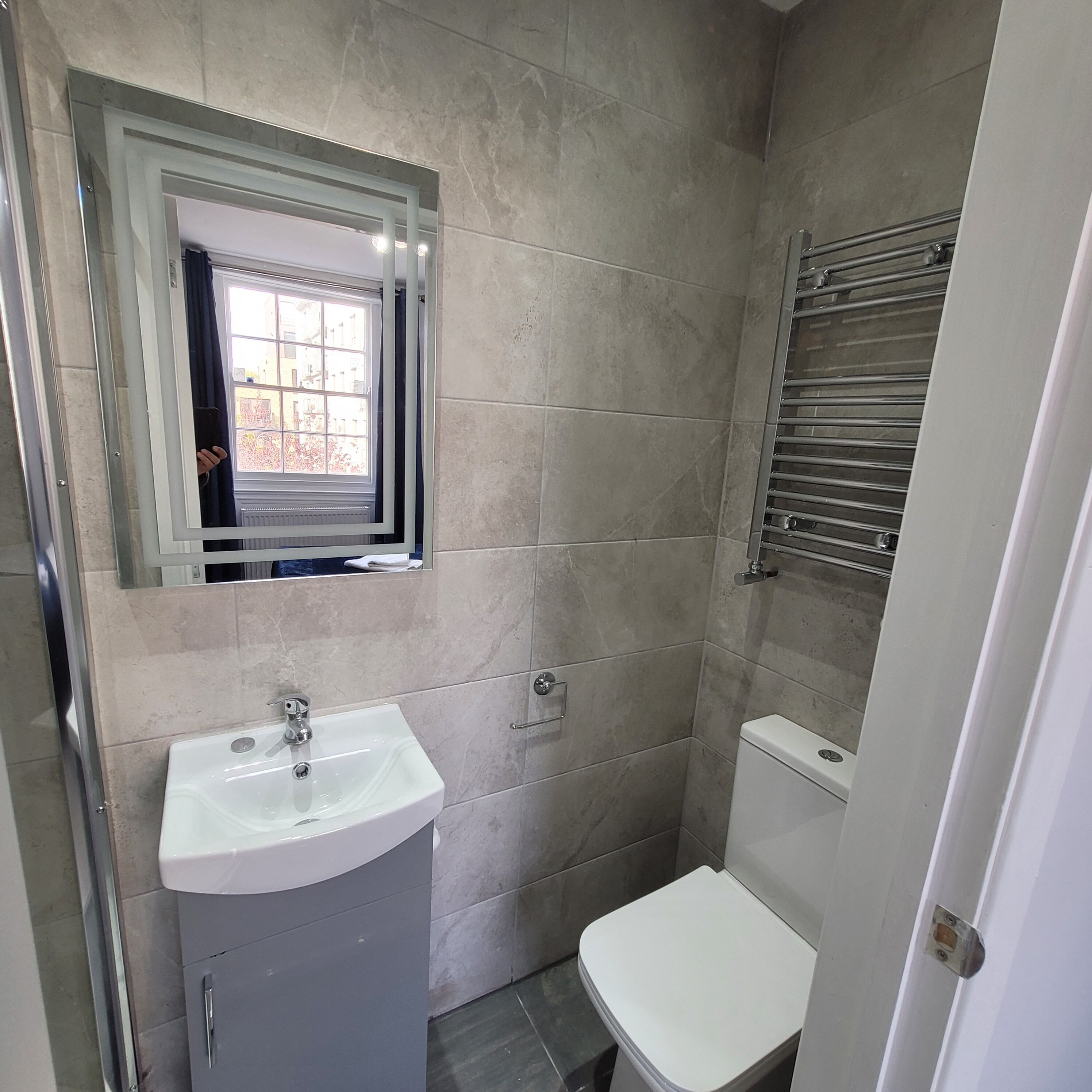 Une salle de bain avec un lavabo blanc, un miroir, des toilettes et un espace douche.