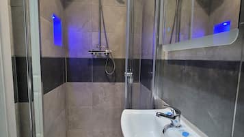 A modern bathroom with a glass-enclosed shower, a white sink, and a mirror.