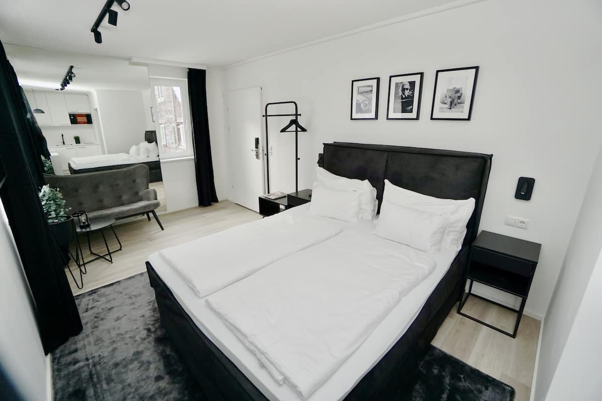 A modern bedroom with a large bed, bedside tables, a desk, and a chair.