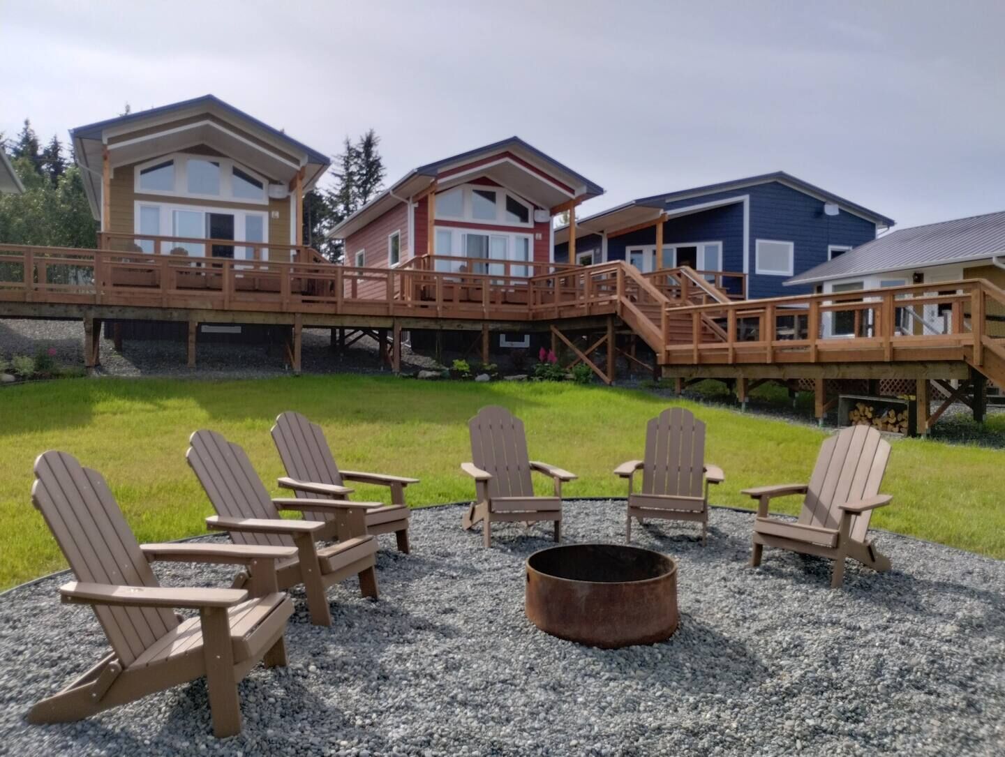 Une cabane dotée d’une terrasse, de meubles de jardin et d’un foyer extérieur.