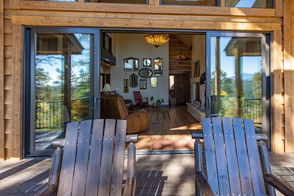A wooden cabin with a glass door leading to a living area with a sofa, chairs, and a fireplace. - AC, Close to Wolf Creek, Quiet! (Pagosa Springs)
