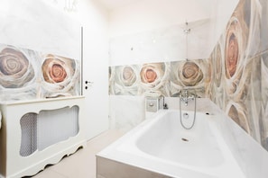 A bathroom with a large bathtub, a shower, and a radiator.