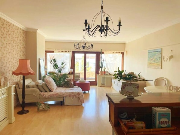 A cozy living room with a sofa, a coffee table, and a chandelier.