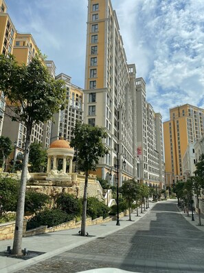 Une rangée d’immeubles modernes de grande hauteur, avec un parc central agrémenté d’un kiosque et d’une fontaine.