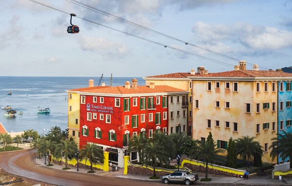 Un hôtel aux couleurs vives, avec un bâtiment d’angle rouge et un autre bâtiment jaune à la façade bleue.