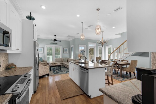 A modern kitchen with a central island, built-in appliances, and a dining area with wooden chairs.