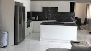 A modern kitchen with white cabinetry, a black backsplash, and a central island. - Beautiful contemporary apartment in the heart of Rodney Bay! (Rodney Bay)
