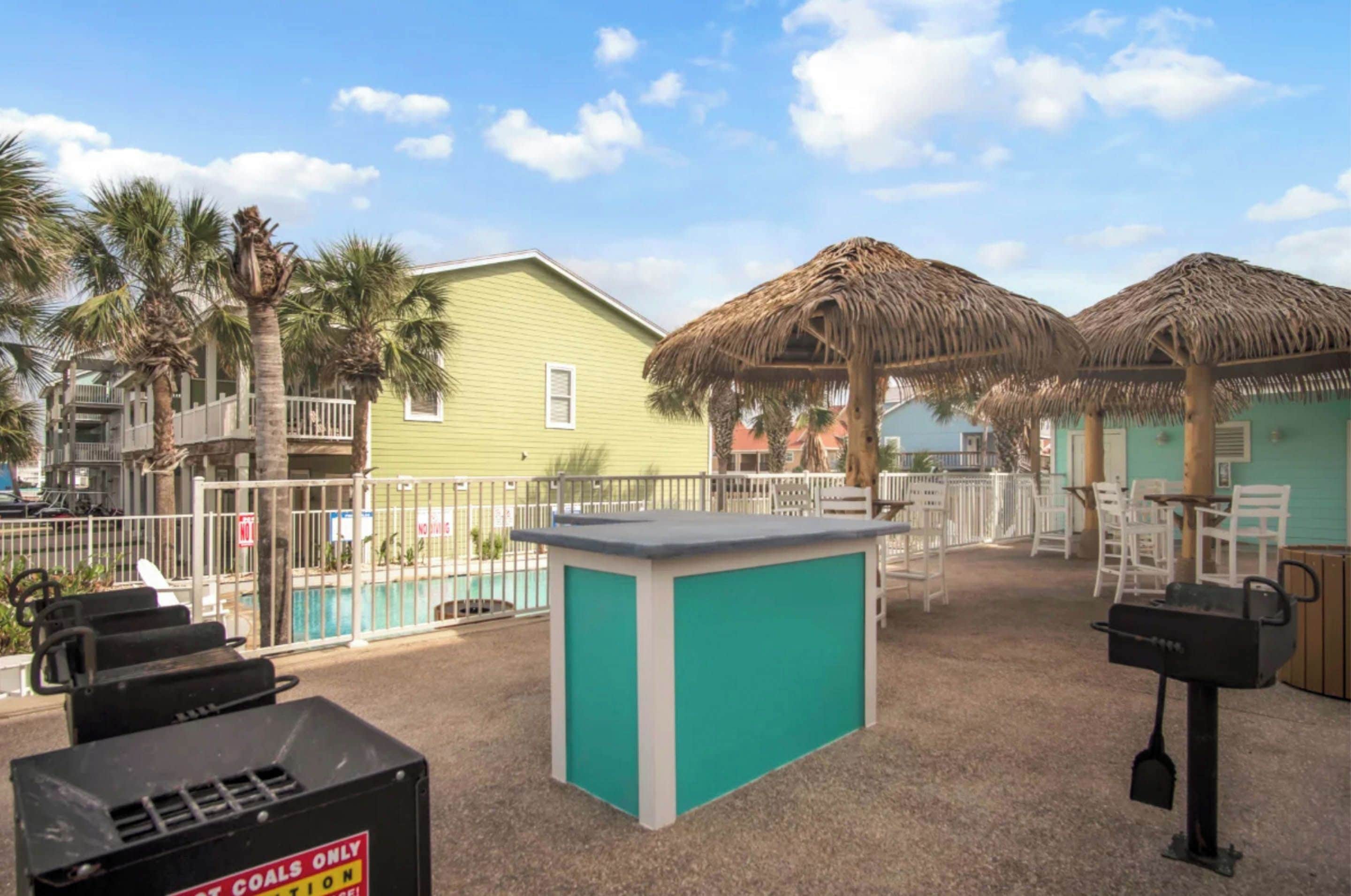 A poolside area with a bar, chairs, and a thatched umbrella.