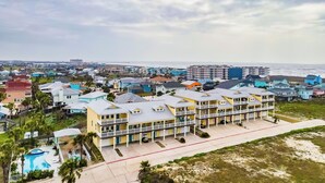Ett hotell vid kusten med flera balkonger, en swimmingpool och utsikt över stranden och havet.
