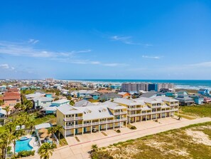 A coastal residential area with beachfront properties, a swimming pool, and a clear view of the ocean.