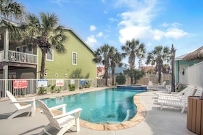 A swimming pool with lounge chairs, a no lifeguard sign, and a fenced area with palm trees. - Sandbar by Silver Sands Vacation Rentals (Port Aransas)