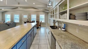 A modern kitchen with a central island, built-in cabinets, and a large window providing natural light. - Sassy Seahorse by Silver Sands Vacation Rentals (Port Aransas)
