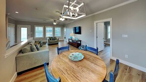 A dining area with a round wooden table, blue chairs, and a ceiling fan. - Sassy Seahorse by Silver Sands Vacation Rentals (Port Aransas)