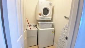 A compact laundry room with a washing machine, a dryer, and a small sink.
