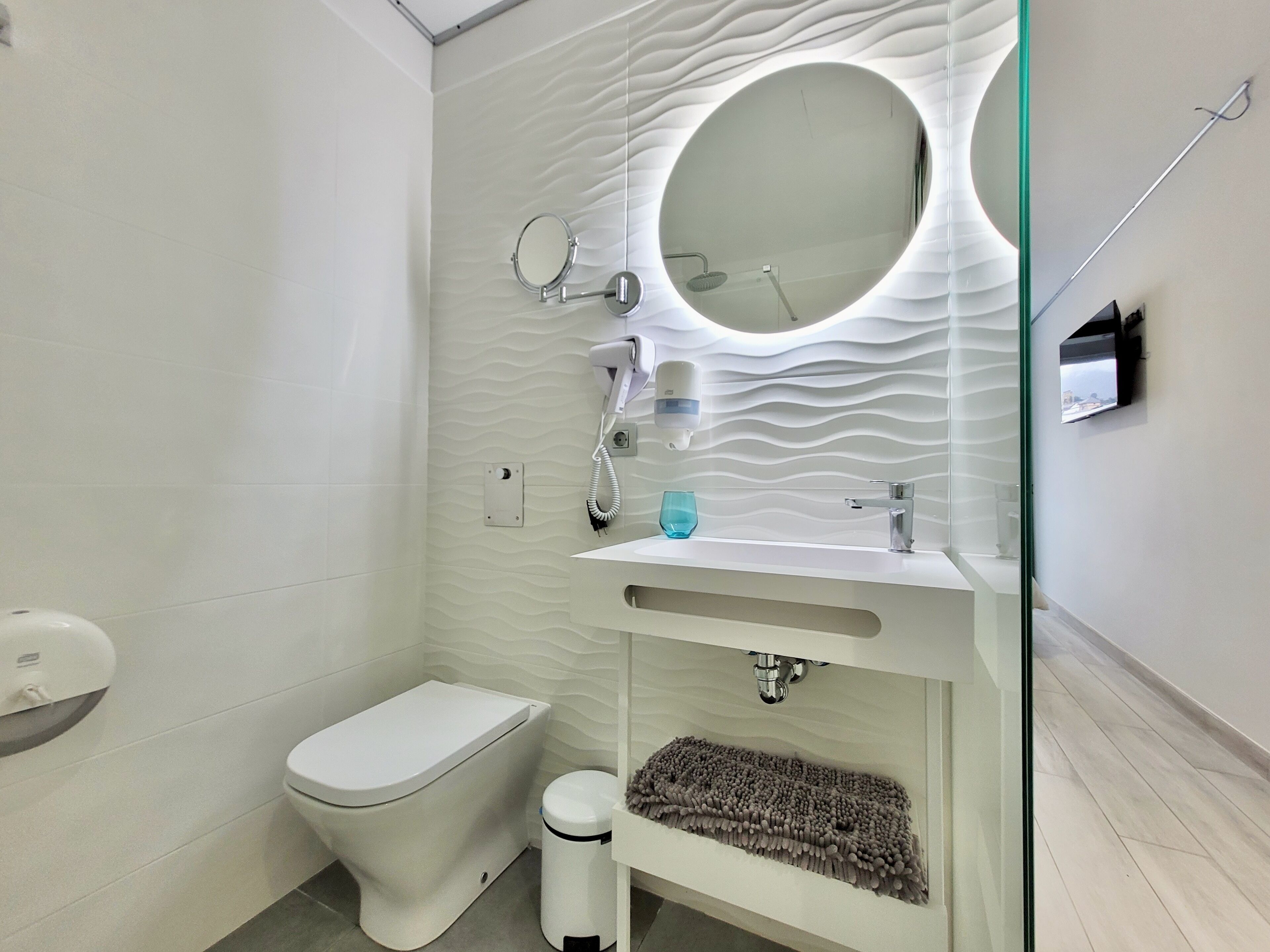 A modern bathroom with a toilet, bidet, and a sink with a mirror above it.