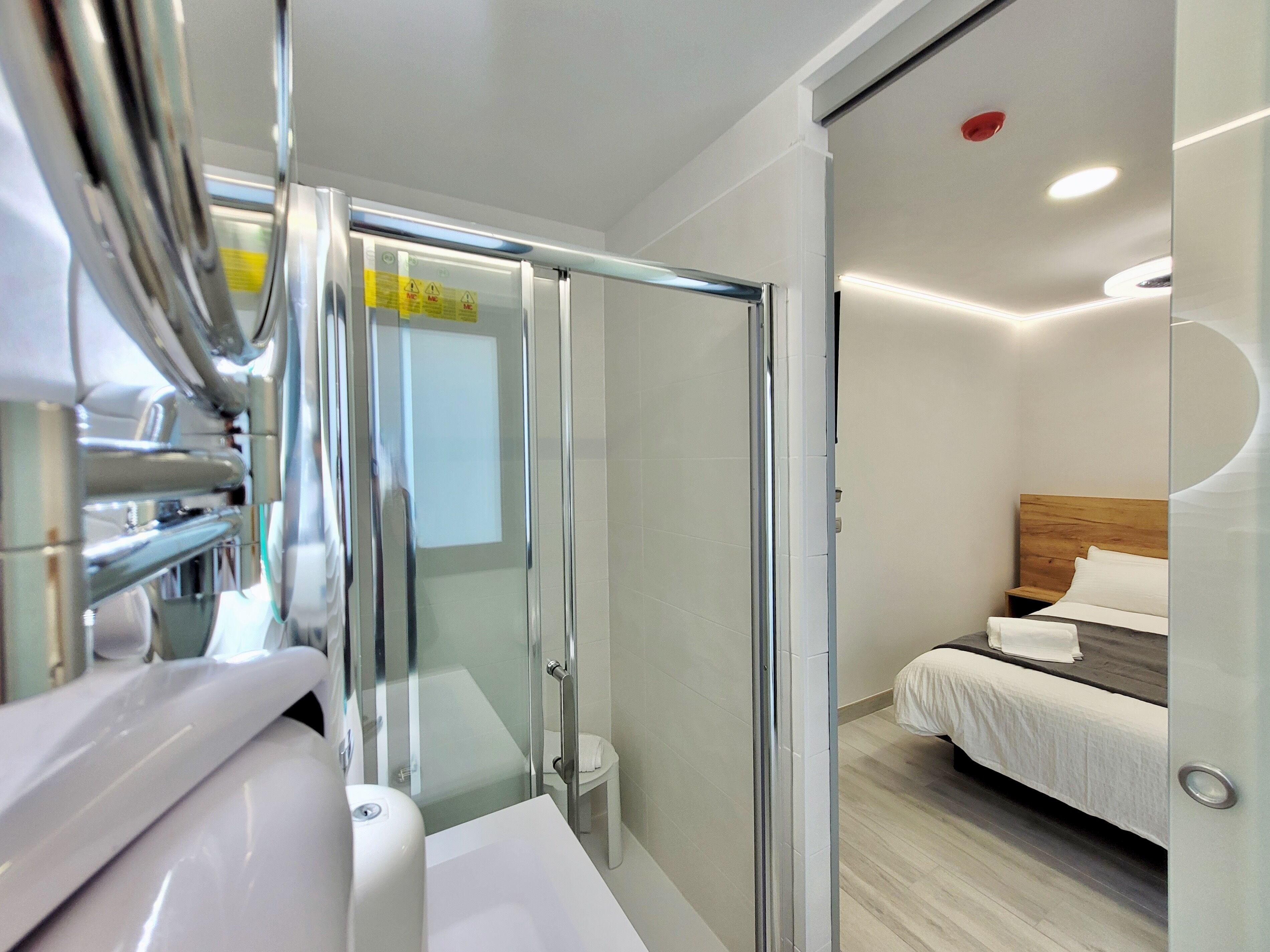 A modern bathroom with a glass shower enclosure, a white sink, and a toilet.