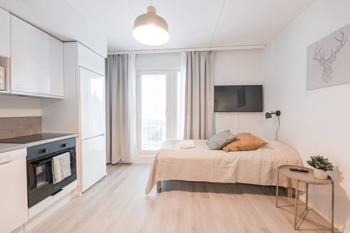 A modern bedroom with a bed, bedside table, and a TV on the wall.