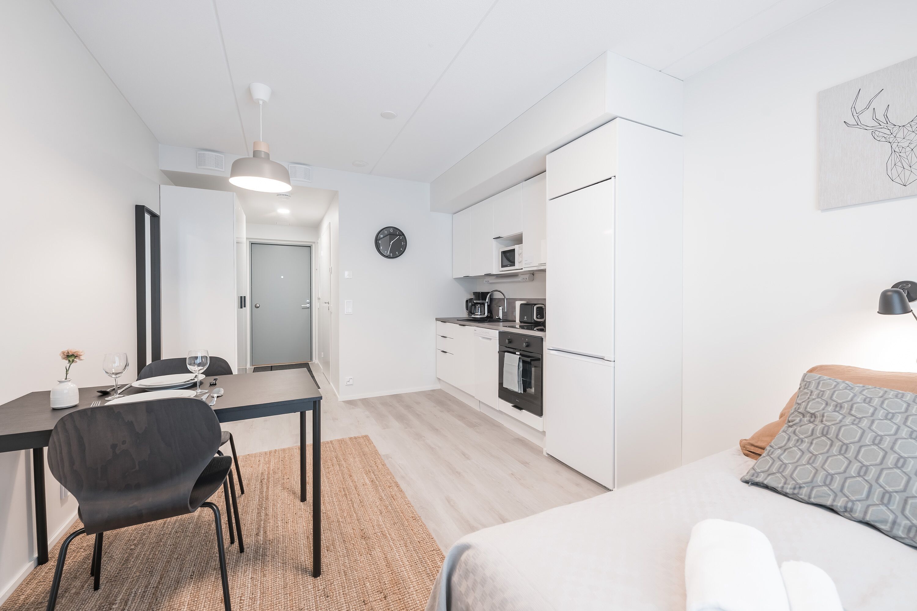 Une chambre moderne et compacte, dotée d’un coin repas, d’une kitchenette et d’un lit.