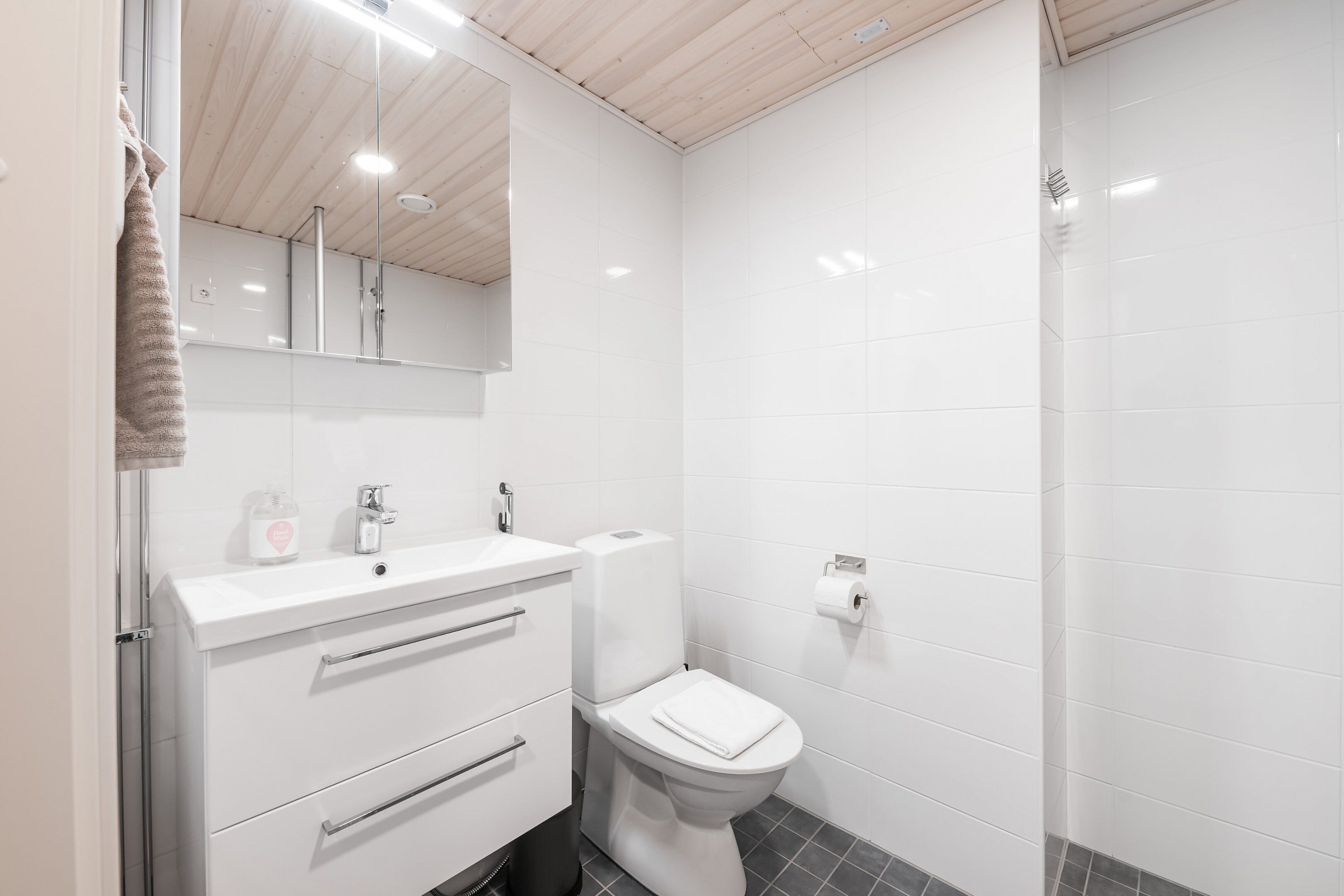 A modern bathroom with a white sink, mirror, and toilet.