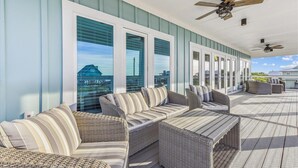 A covered outdoor seating area with wicker furniture and large windows offering views of the cityscape.