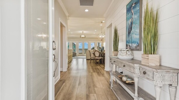 A spacious hallway with wooden flooring, a dining area in the background, and a wall-mounted painting.